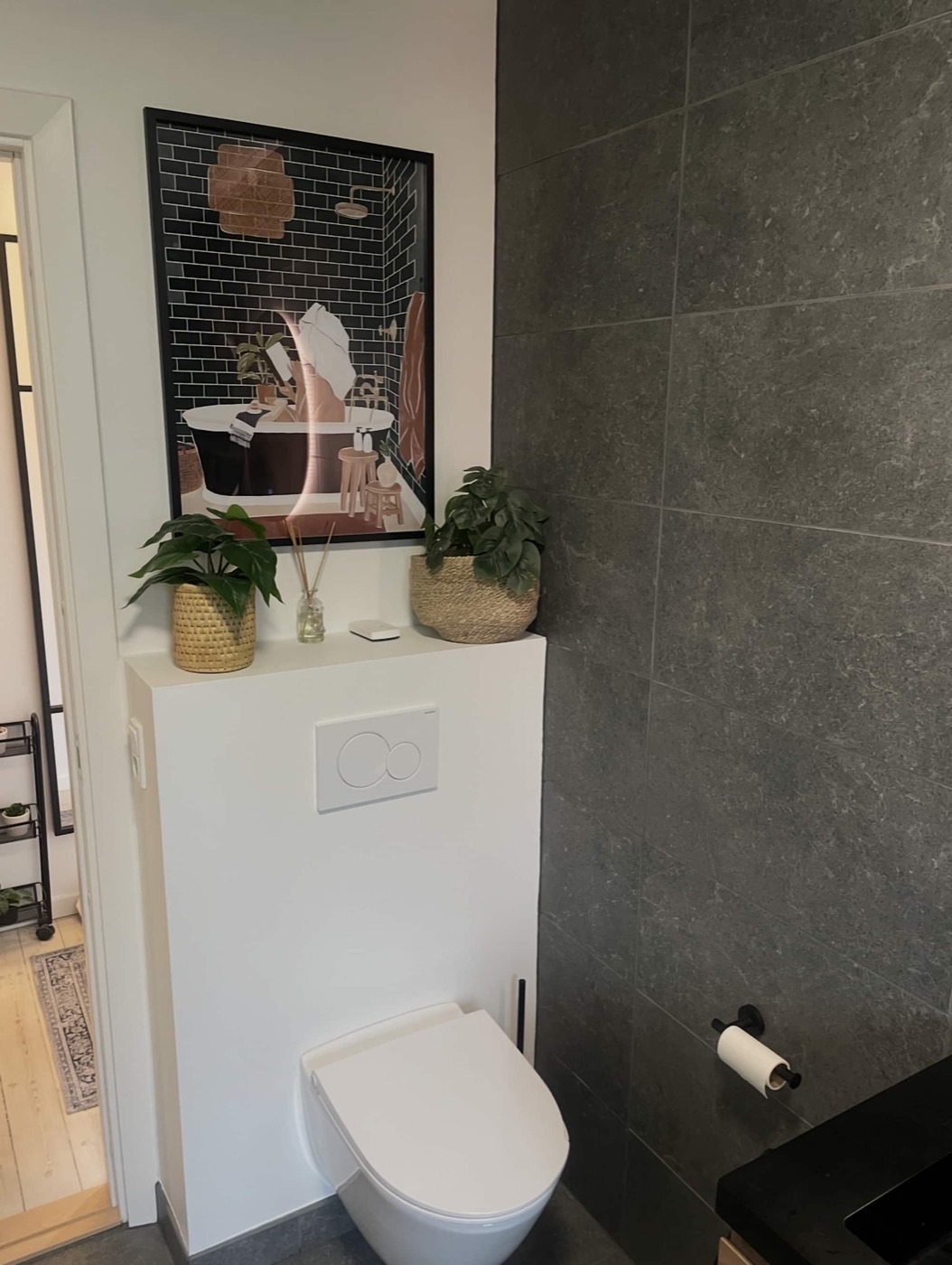 Vægophængt toilet med indbygget cisterne og mørkegrå storformatfliser